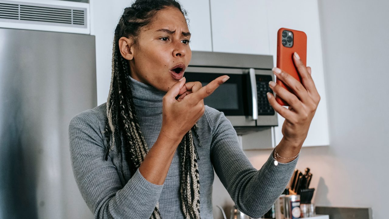Femme agacée face à un appel sur son téléphone, dans sa cuisine
