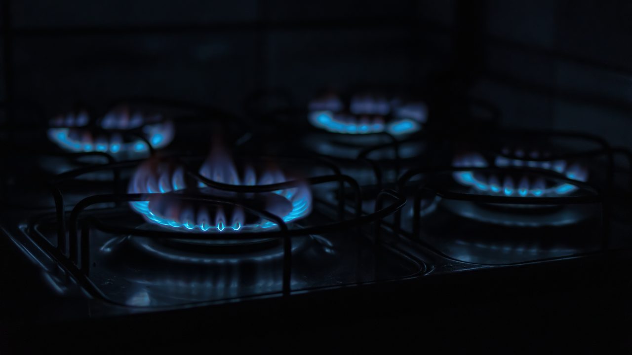 Brûleurs d’une gazinière allumés, flammes bleues dans la pénombre